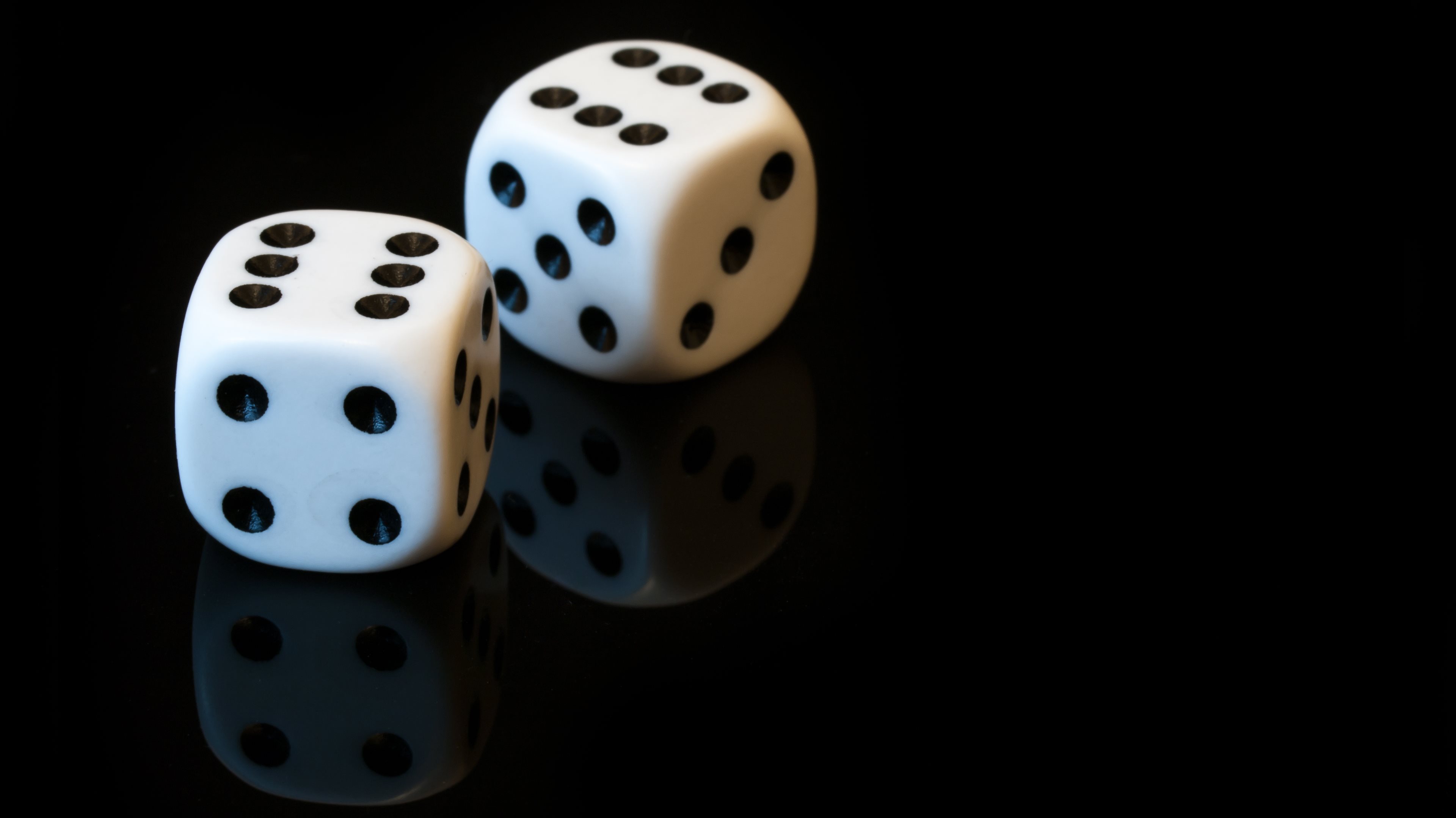 Pair of white dice on a black reflective background